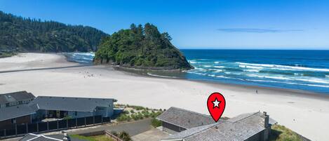 A coastal property with a beach view, a fenced yard, and a building with a sloped roof.