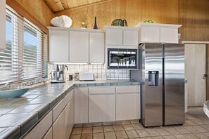 Eine moderne Küche mit weißen Schränken, einem Edelstahlkühlschrank und einem eingebauten Backofen.
