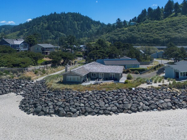 Uma área residencial costeira com casas, uma linha costeira rochosa e uma colina arborizada ao fundo.