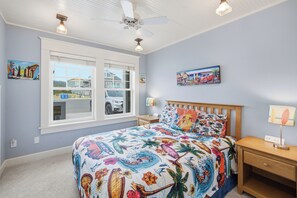Ein Schlafzimmer mit einem großen Bett, einem Holz-Kopfteil, einem Nachttisch, einem Schreibtisch und einem Deckenventilator.