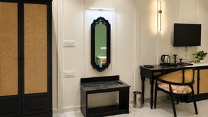 Une pièce comprenant un grand placard, un miroir, un bureau avec une chaise, une télévision et une petite table.