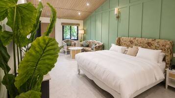 Un dormitorio con una cama grande, un sofá, una mesita y una planta en maceta.