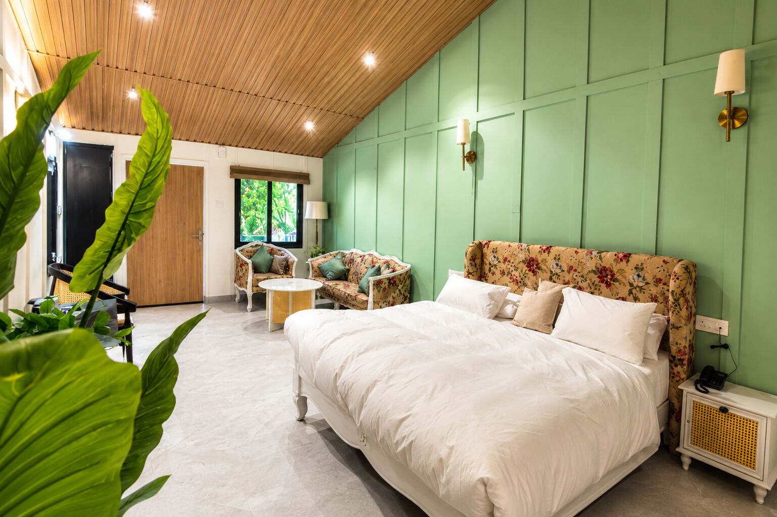 A bedroom with a large bed, two chairs, a small table, and a nightstand.