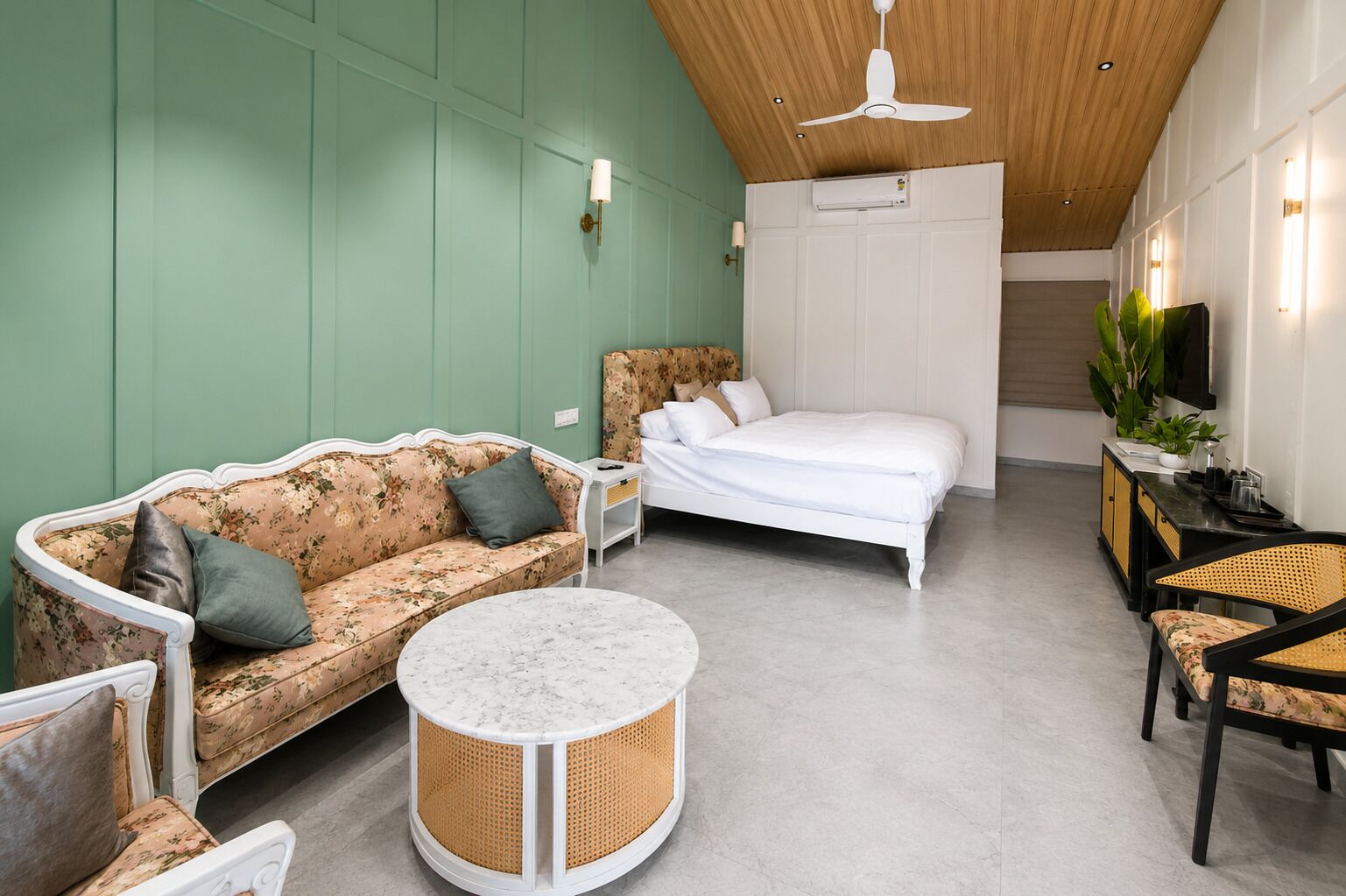 A modern room with a sofa, a bed, a round table, and a TV.