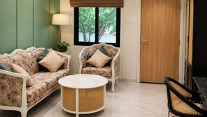 Une pièce comprenant un canapé, deux fauteuils, une table basse ronde et une porte.