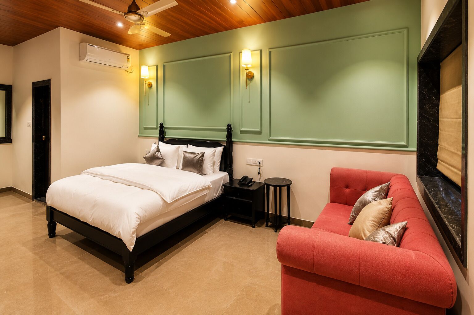 Un dormitorio con cama, mesita de noche, sofá rojo y aire acondicionado instalado en la pared.