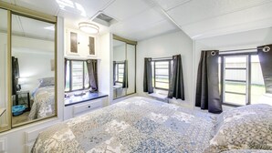 A bedroom with a large bed, a dresser, a mirror, and a window with curtains. - Fish, Hunt & Explore! Mtn-View Tiny Home in Noxon (Noxon)