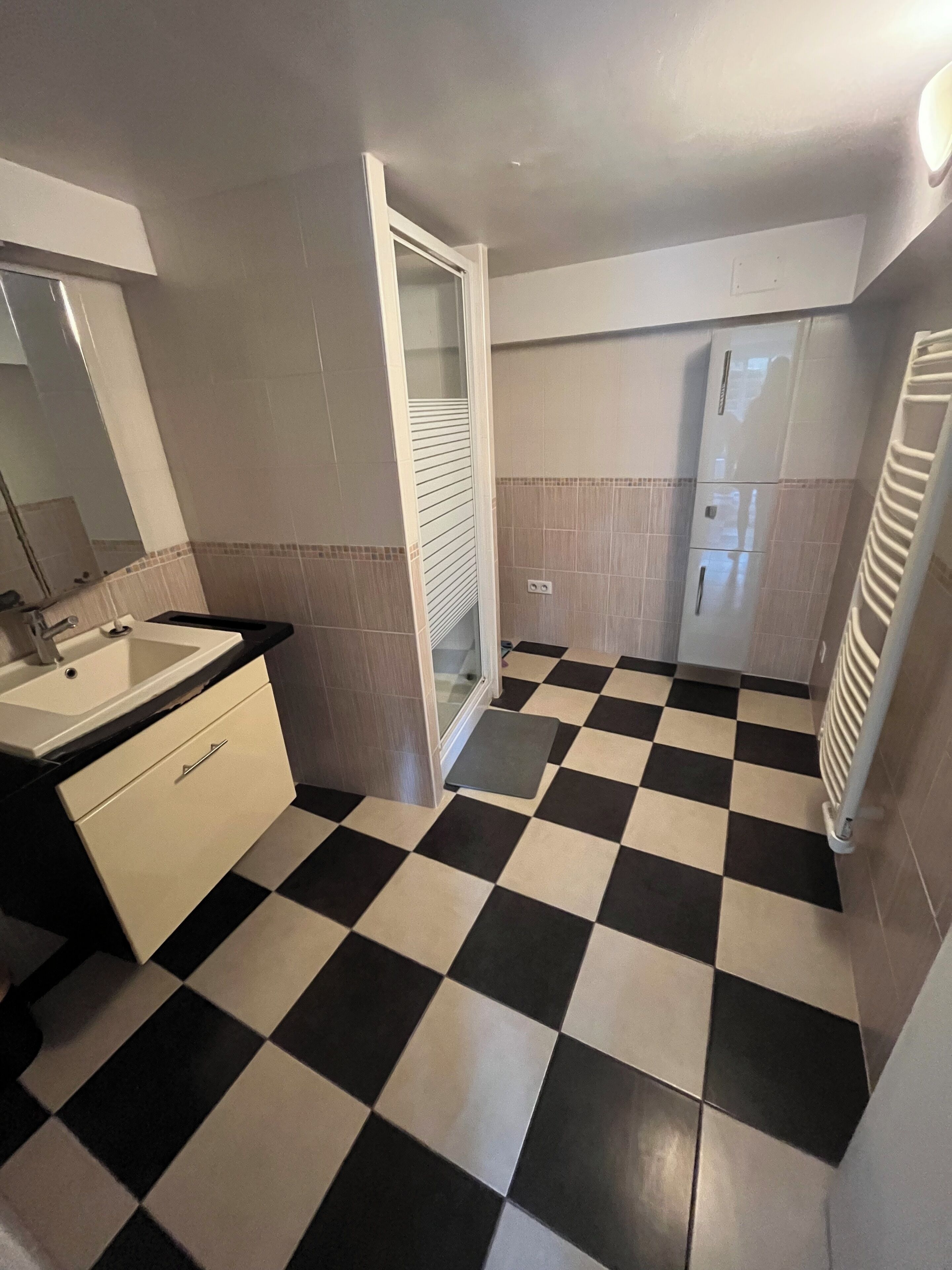 A bathroom with a checkered floor, a sink, a mirror, and a toilet.