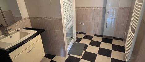 A bathroom with a checkered floor, a sink, a mirror, and a toilet.