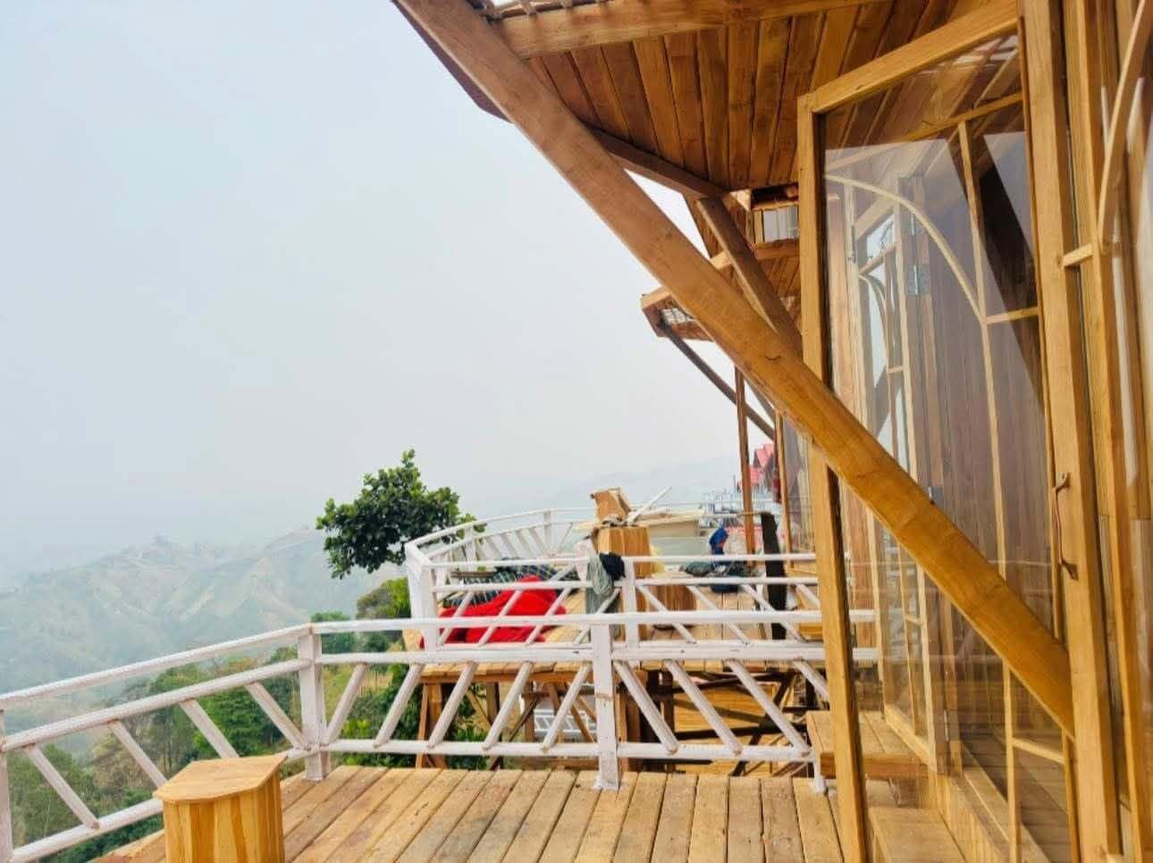 A wooden deck with a railing, a glass door, and a view of the landscape.