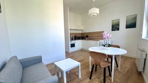 A modern kitchen with white cabinets, a dining table with wicker chairs, and a small white table.