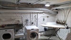 Une buanderie équipée de deux machines à laver, d’un évier et d’un étendoir.