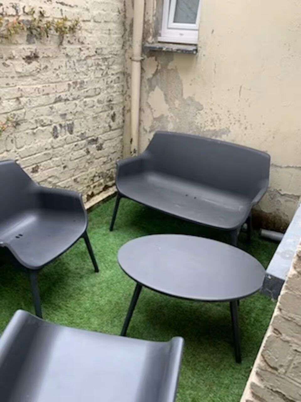 A small outdoor seating area with a round table and two benches.