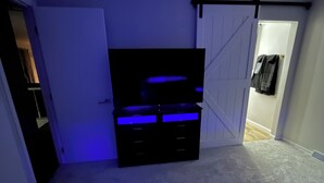 A room with a bed, a dresser, a door, and a wall-mounted rack. - Luxury Entertainers Escape—Game Room + Lounge (Davenport)