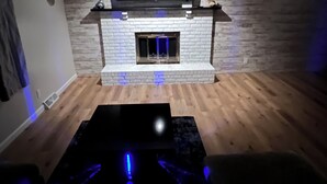 A living room with a fireplace, a flat-screen TV mounted above it, and a wooden floor. - Luxury Entertainers Escape—Game Room + Lounge (Davenport)