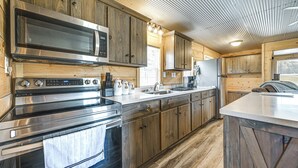 A modern kitchen with stainless steel appliances, wooden cabinetry, and a large island. - Fire Pit, Grill! Mammoth Cave Cabin Near Boat Ramp (Mammoth Cave)