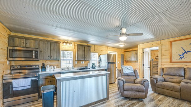 A modern kitchen with stainless steel appliances, a wooden island, and a seating area with leather chairs. - Fire Pit, Grill! Mammoth Cave Cabin Near Boat Ramp (Mammoth Cave)