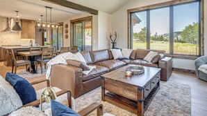 A spacious living area with a large sectional sofa, a coffee table, and a dining area with wooden furniture. - Granby Mtn Retreat w/ Ski Hill Views, Hot Tub (Granby)