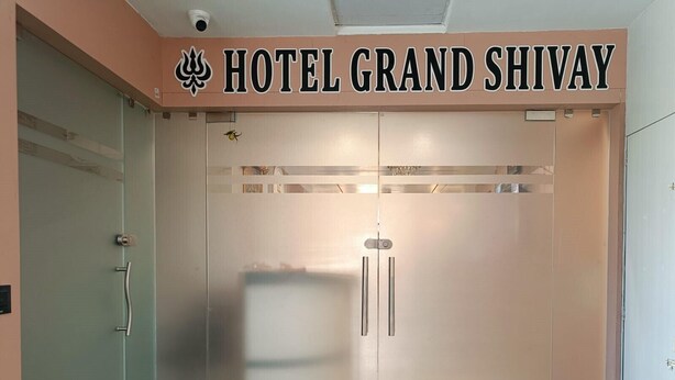 Entrada de un hotel con puerta de vidrio esmerilado y un cartel que dice 'HOTEL GRAND SHIVAY'.