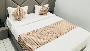 Una habitación de hotel con cama, mesita de noche, aire acondicionado de pared y ventilador de techo.