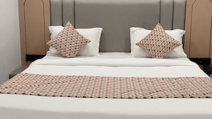 Un dormitorio moderno con una cama grande, un cabecero con líneas verticales, un cuadro abstracto colgado en la pared y una manta decorativa.