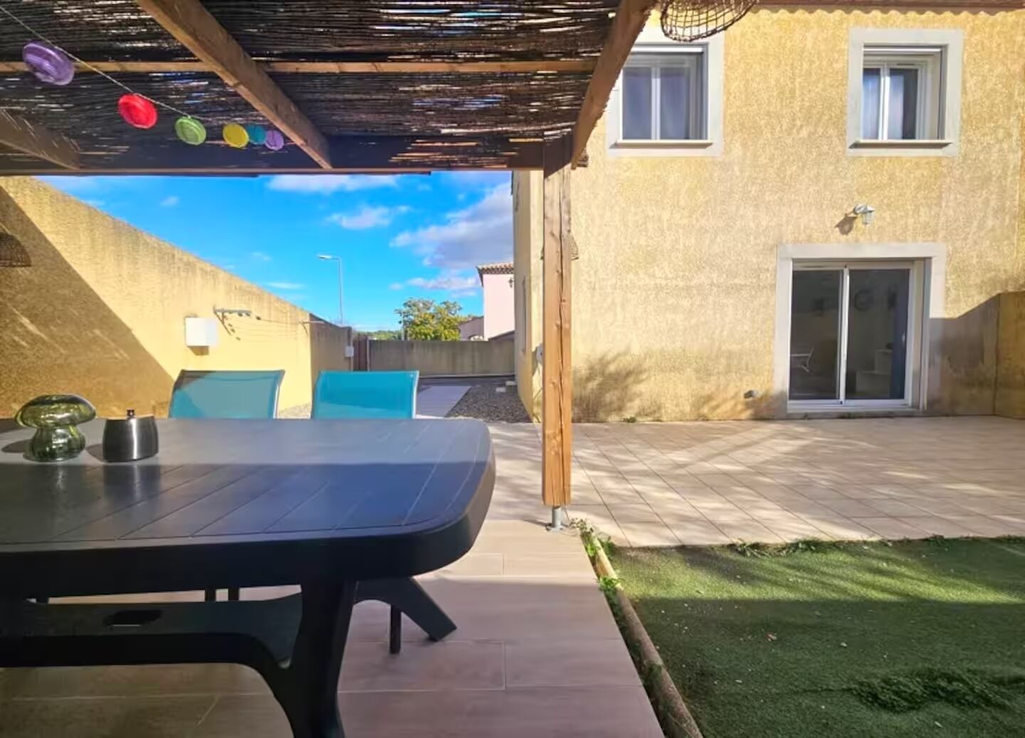 Un espace extérieur aménagé avec une table, des chaises et une pergola.