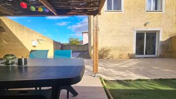 Un espace extérieur aménagé avec une table, des chaises et une pergola.