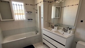 A bathroom with a bathtub, a shower, a toilet, a sink, and a mirror.