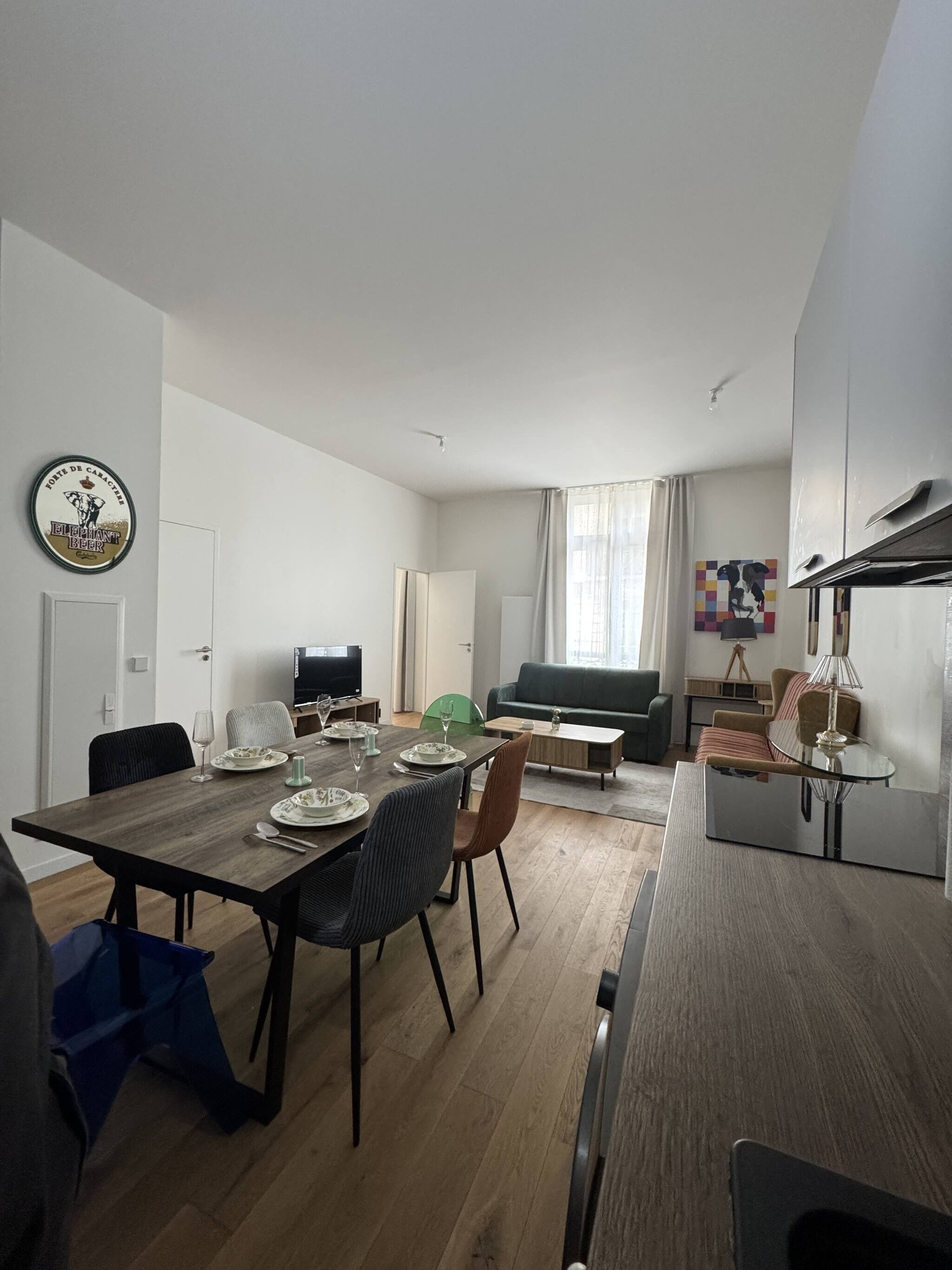 Un salon moderne comprenant un coin repas, un téléviseur à écran plat, un canapé et une table basse.