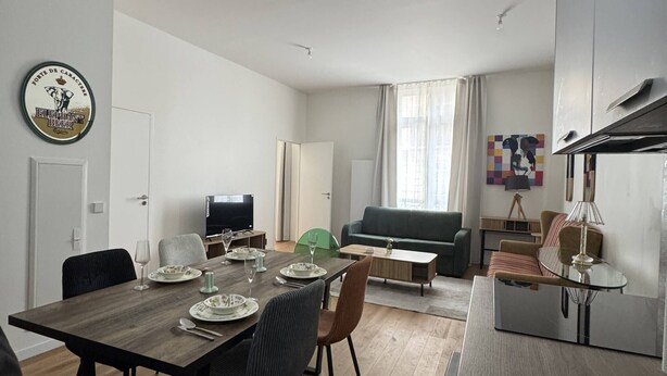 A modern living room with a dining area, a flat-screen TV, a sofa, and a coffee table. - Elegant 2-Bedroom Apartment in the Heart of Paris (Paris)