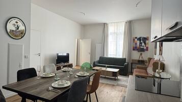 Un salon moderne comprenant un coin repas, un téléviseur à écran plat, un canapé et une table basse.
