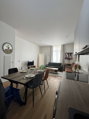 Een moderne woonkamer met een eethoek, een flatscreen televisie, een bank en een salontafel.