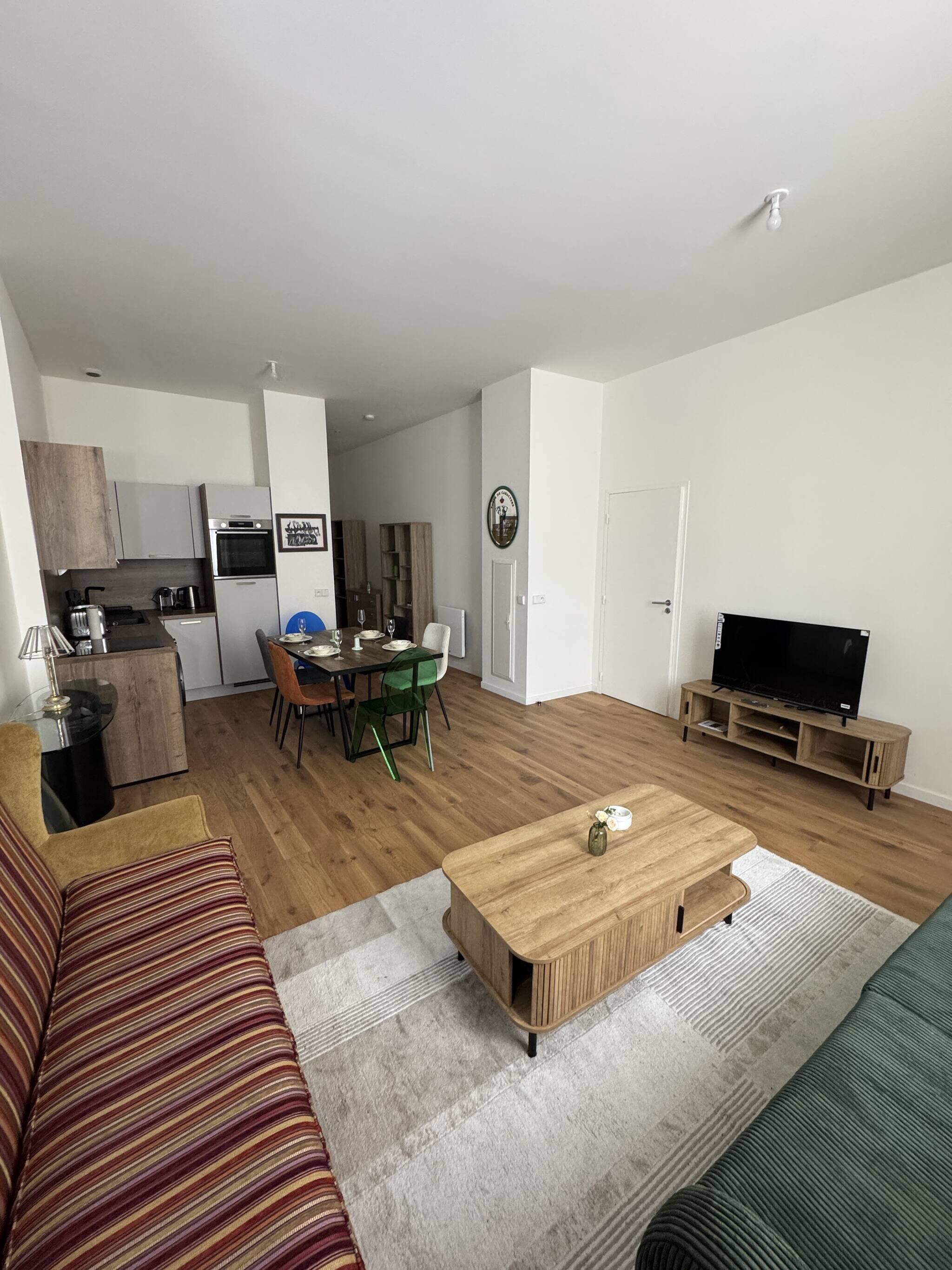 Un salon moderne comprenant un canapé, une table basse, un meuble pour la télévision et un coin repas avec des chaises et une table.