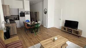 A modern living room with a sofa, a coffee table, a TV stand, and a dining area with chairs and a table. - Elegant 2-Bedroom Apartment in the Heart of Paris (Paris)