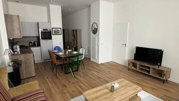 Un salon moderne comprenant un canapé, une table basse, un meuble pour la télévision et un coin repas avec des chaises et une table.