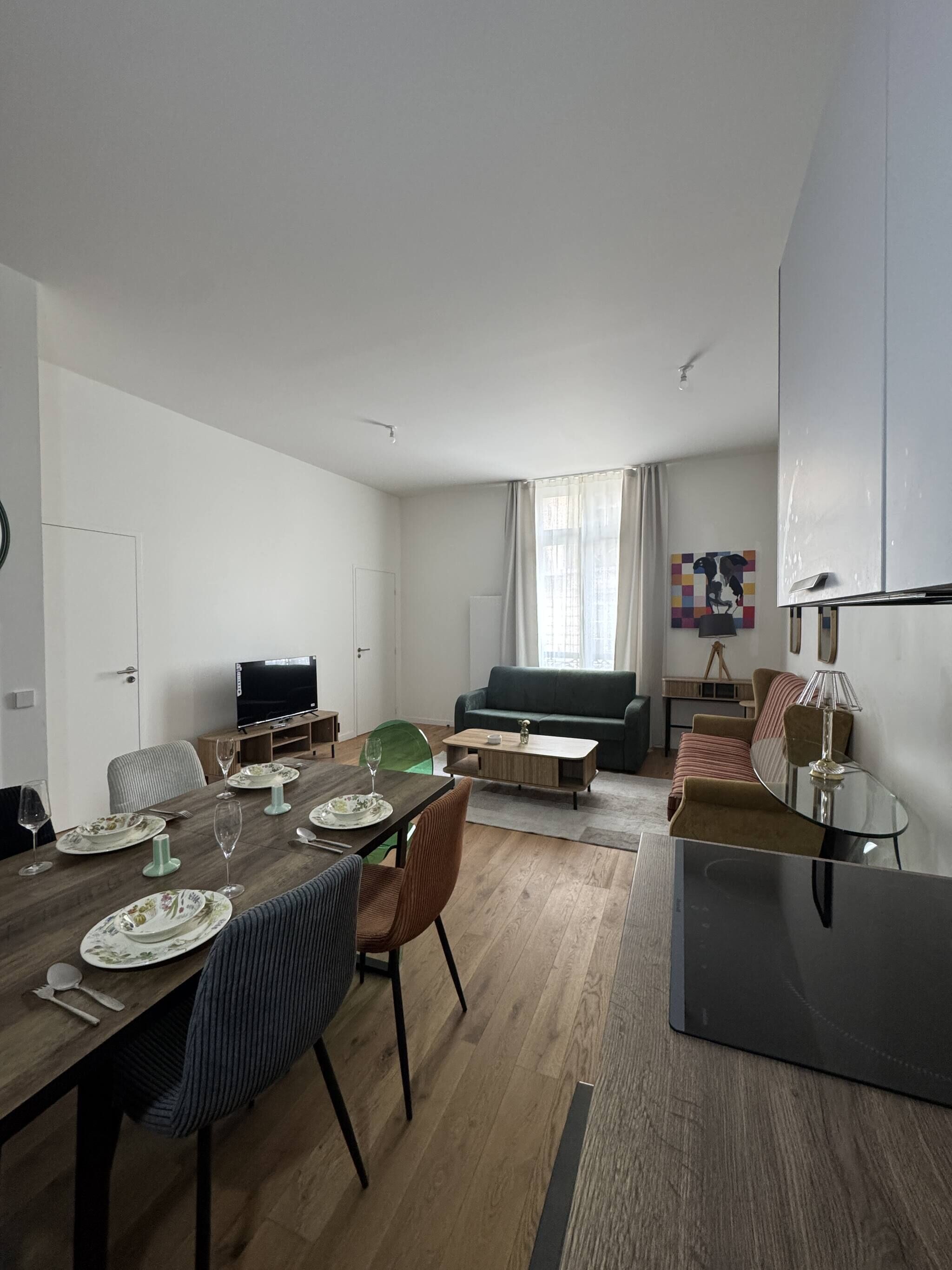 Un salon moderne comprenant un coin repas, un canapé, un téléviseur et une lampe.