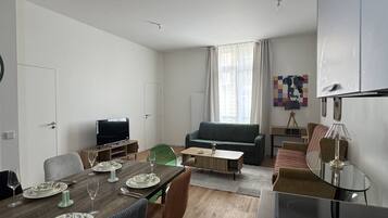 Un salon moderne comprenant un coin repas, un canapé, un téléviseur et une lampe.