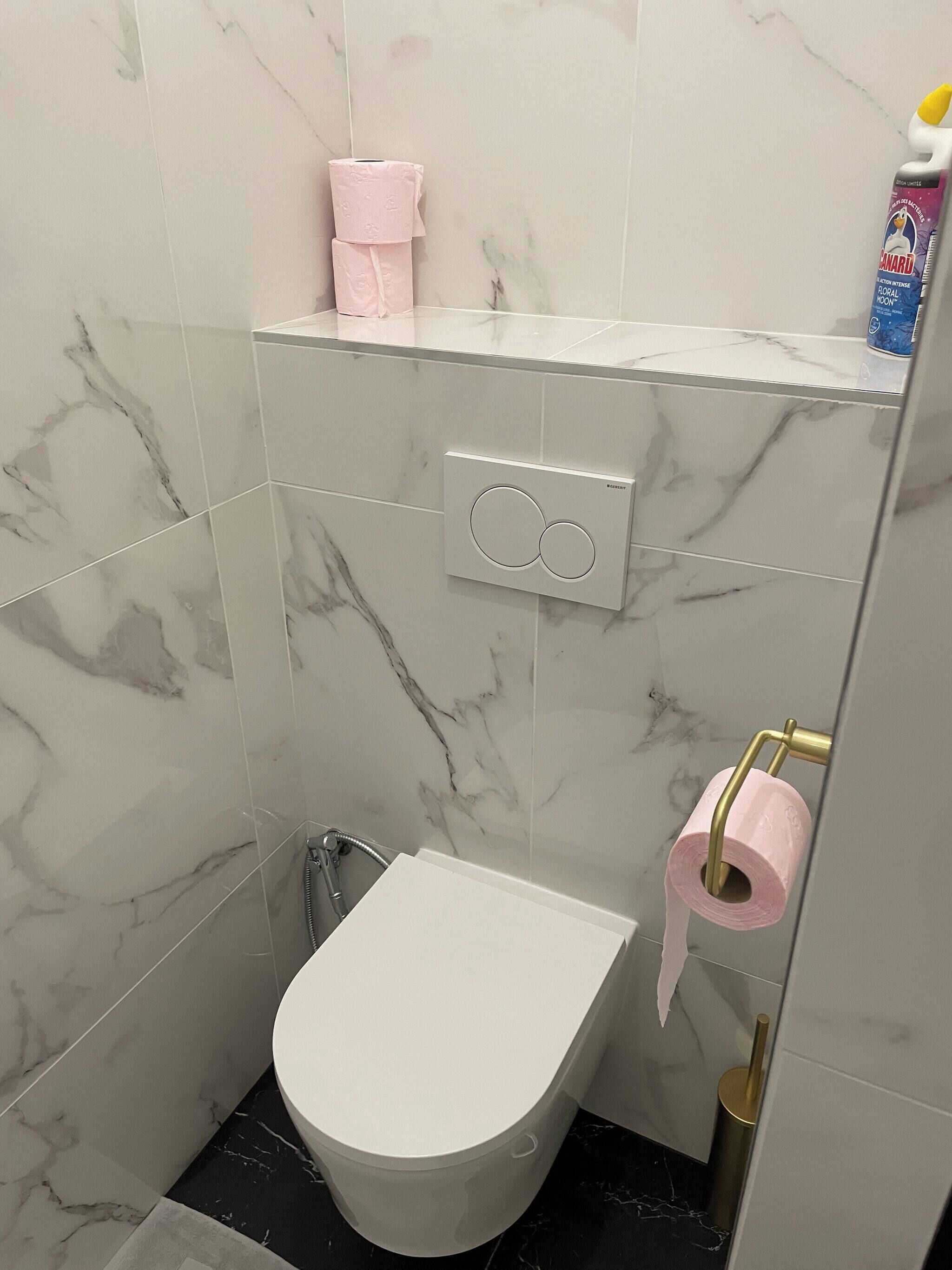 Une salle de bain équipée de toilettes, d’un bidet et d’un porte-rouleau de papier toilette.