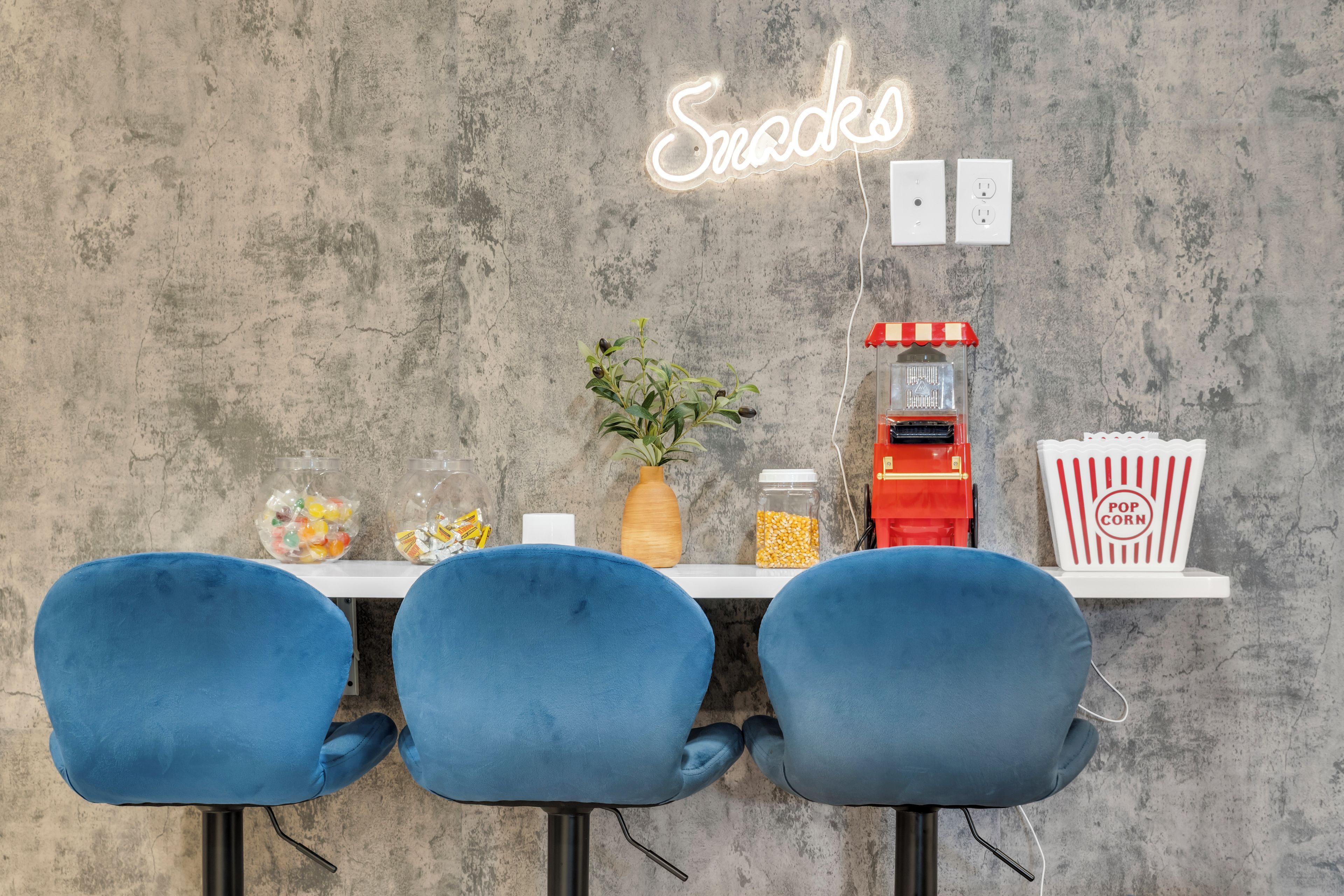 Un bar servant des collations, avec une enseigne au néon, un appareil à pop-corn et un bocal rempli de pop-corn.
