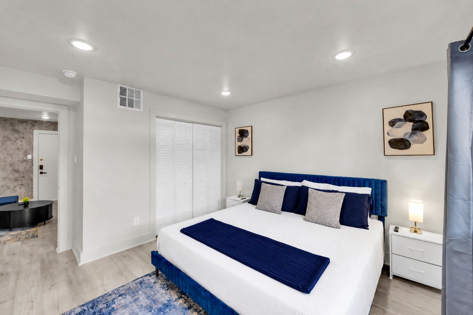 A bedroom with a large bed, bedside tables, a desk, and a chair.