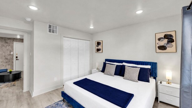 A bedroom with a large bed, bedside tables, a desk, and a chair. - Renovated 2BR - Sleeps 6 - Walk to Deep Ellum/DT (Dallas)