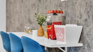 A white table with a popcorn machine, a vase with a plant, and a popcorn container. - Renovated 2BR - Sleeps 6 - Walk to Deep Ellum/DT (Dallas)