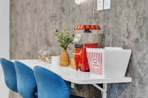 A white table with a popcorn machine, a vase with a plant, and a popcorn container. - Renovated 2BR - Sleeps 6 - Walk to Deep Ellum/DT (Dallas)