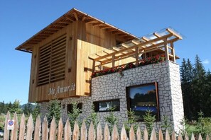 A wooden building with a stone base, labeled 'Mi Amuritt,' and a wooden picket fence in front. - Chalet Mi Amur (Badia)