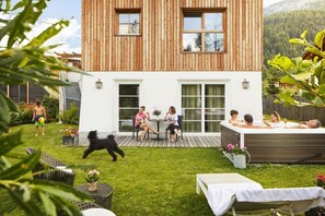 A modern house with a wooden exterior, a patio with outdoor seating, and a hot tub. - Chalet Mi Amur (Badia)