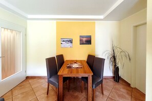 A dining area with a wooden table and four chairs, two wall-mounted pictures, and a potted plant. - Near the beach & newly renovated: Vacation rental at Küstenwaldhaus Koserow - (Koserow)