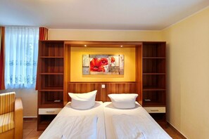A hotel room with a bed, two white pillows, a wooden headboard, a painting above the bed, and a window with curtains. - Near the beach & newly renovated: Vacation rental at Küstenwaldhaus Koserow - (Koserow)