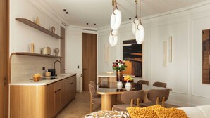A modern kitchen with a built-in island, wooden cabinetry, and a dining area with a table and chairs. - Luxury Apt Climatise - 6p/3bdr - Arc de Triomphe (Paris)