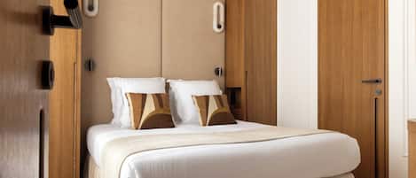 A neatly made bed with a headboard, a wooden wardrobe, and a door with a handle.
