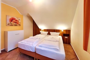 A hotel room with two beds, a wooden headboard, a painting on the wall, and a desk. - Pinguin Vacation Rental – Where Nature, a Sauna, and the Sea Await You - Küstenwaldhaus (Koserow)